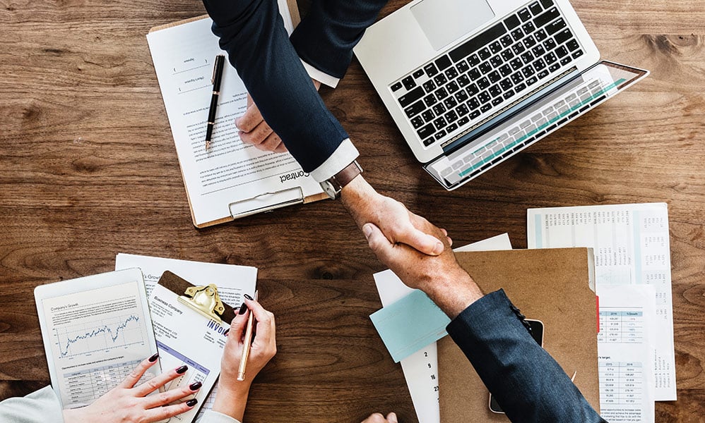 A merchant shaking hands with a merchant services provider after signing the credit card processing contract