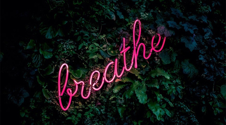 Neon pink sign that spells word breathe