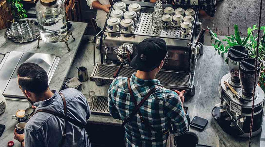 Two men preparing coffee at a coffee shop counter