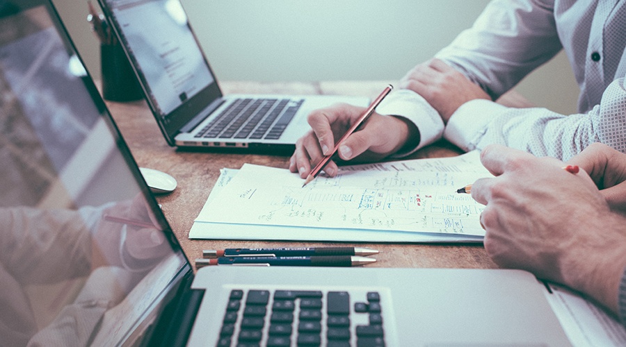 Two people holding pencils and going over payment processing notes