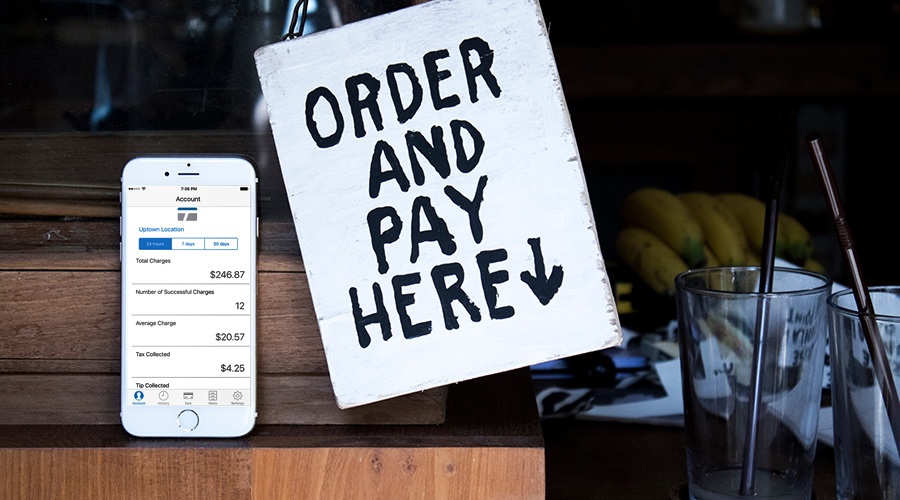 TransNational Payments mobile payment app next to a order and pay here sign at a small business location