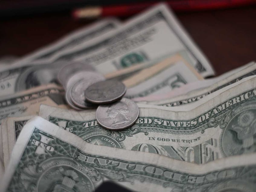 Close up of dollar bills with several quarters on top