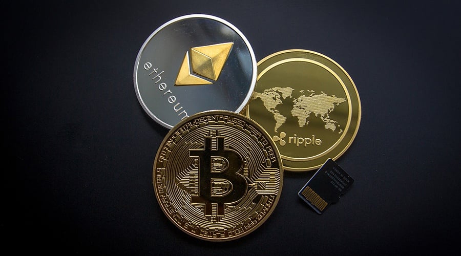 Bitcoin, ethereum and ripple coins stacked next to a SIM card